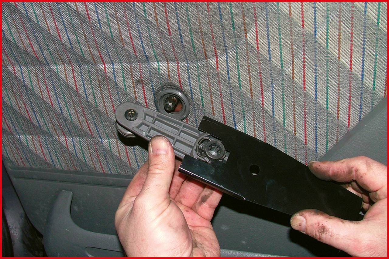 Eine Person hält ein Autoinnenraumelement. Die Türverkleidung ist sichtbar. Hände sind leicht verschmutzt, was auf Autoreparatur hindeutet.