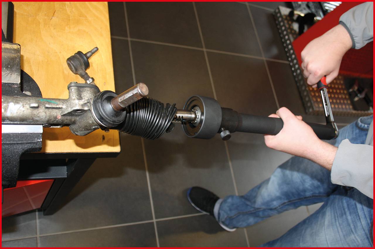 Person arbeitet mit Werkzeug an einer Metallstange, wahrscheinlich in einer Werkstatt. Fokus liegt auf dem Gerät, das bearbeitet wird.