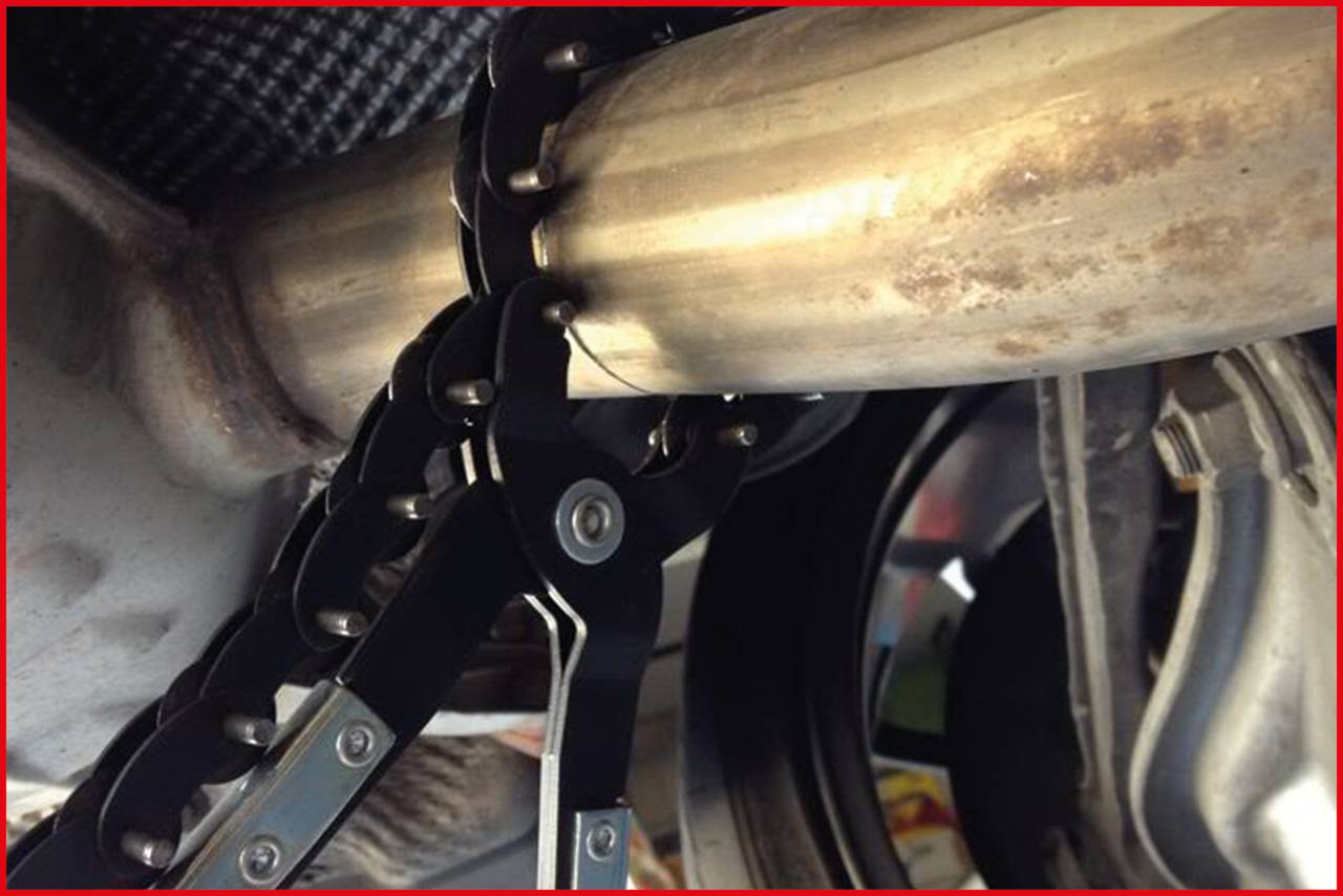 Eine Metallkette hält ein Rohr, das Teil eines Auspuffs ist. Die Kette scheint aufgrund von Arbeiten oder Reparaturen befestigt zu sein.