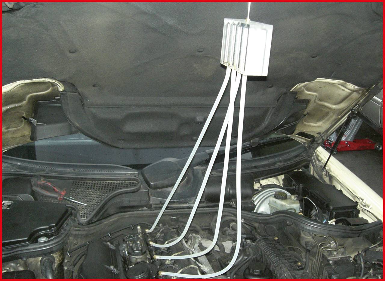 Ein offener Motorraum eines Autos mit mehreren Schläuchen, die von oben in den Motor führen. Auto-Diagnose oder Wartung wird durchgeführt.