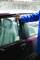 Eine Person mit blauer Jacke öffnet die Tür eines burgunderroten Autos mit einem langen Werkzeug. Der Sitz ist mit Plastik abgedeckt.