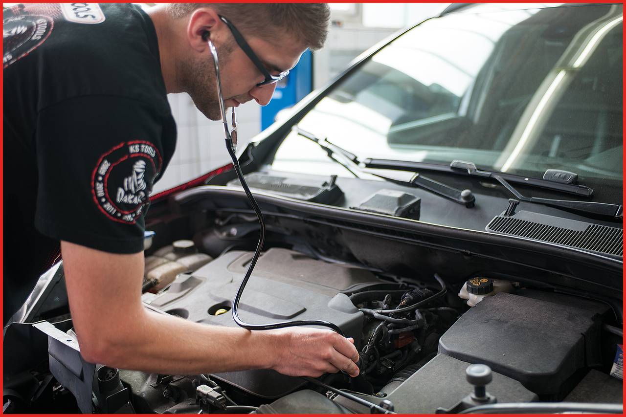 Ein Mechaniker hört mit einem Stethoskop den Motor eines Autos ab, um ein mechanisches Problem zu diagnostizieren.