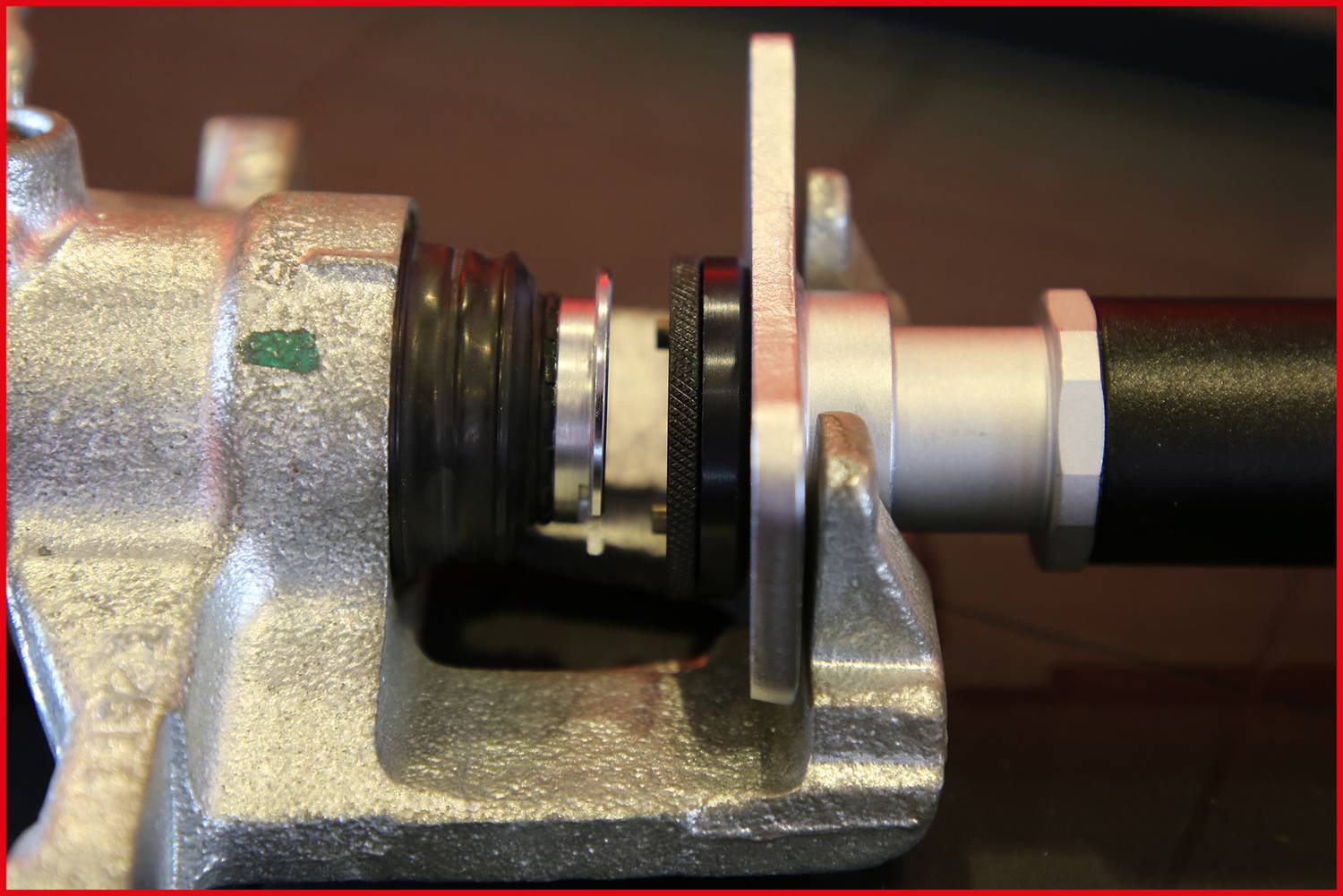 Montage eines mechanischen Bauteils mit einer silbernen Metallhalterung und einer schwarzen Rohrverbindung, Nahaufnahme.