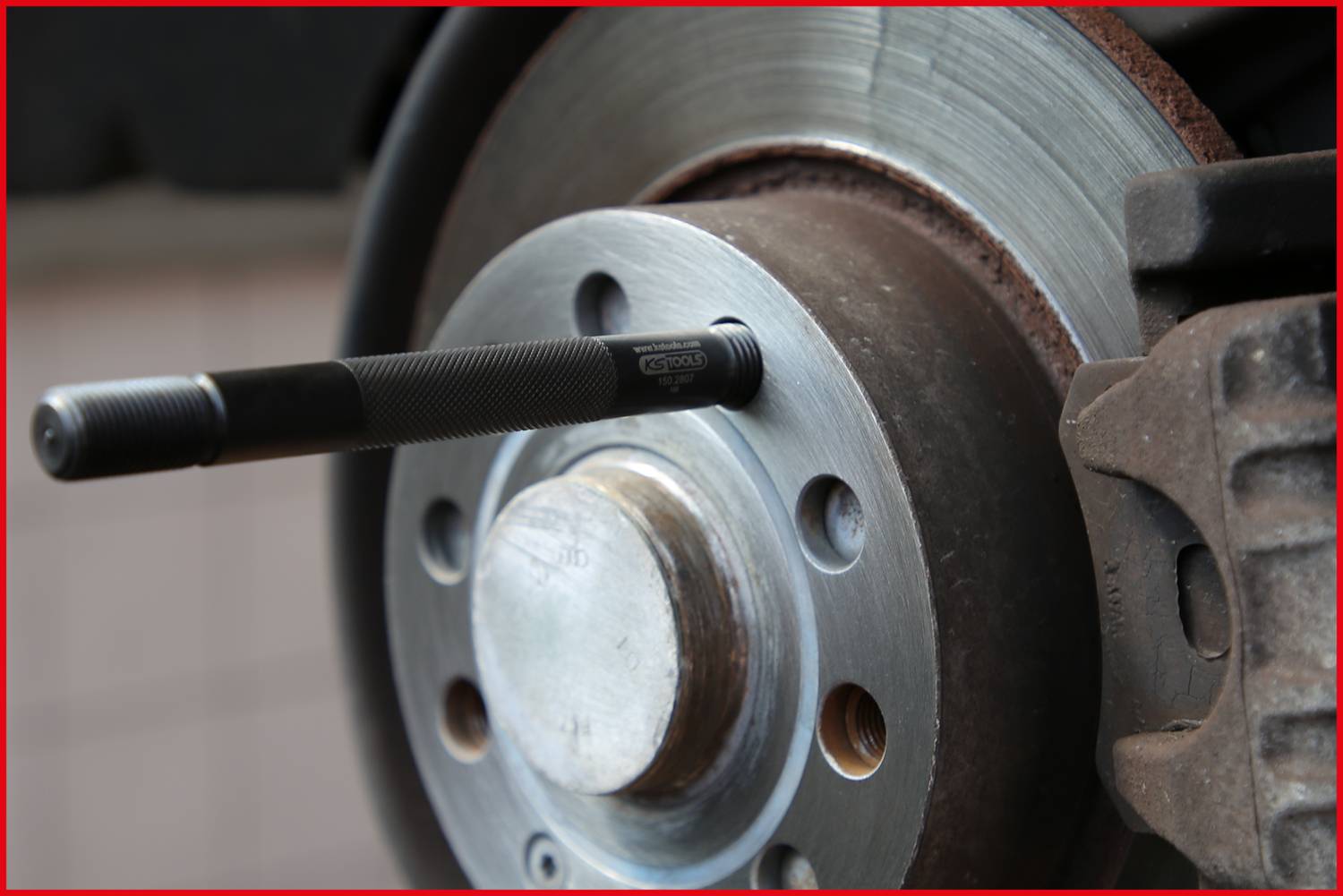 Autoreifen-Montage mit eingebauter Bremsscheibe und Montagewerkzeug. Vorderansicht zeigt Details des Radnabenbereichs.