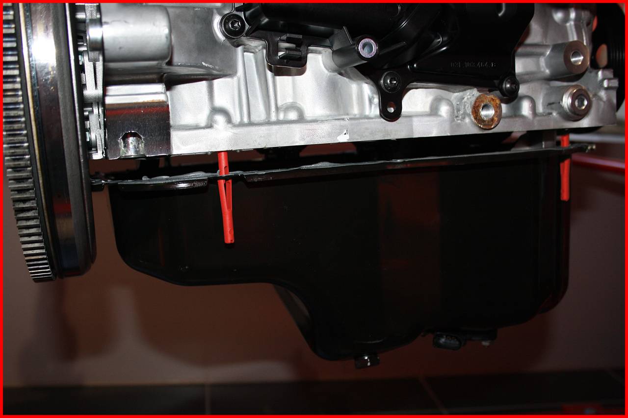 Ein Autoölfiltergehäuse aus Metall und Kunststoff, montiert an einem Motorblock. Der Filter ist unten am Motor angebracht.