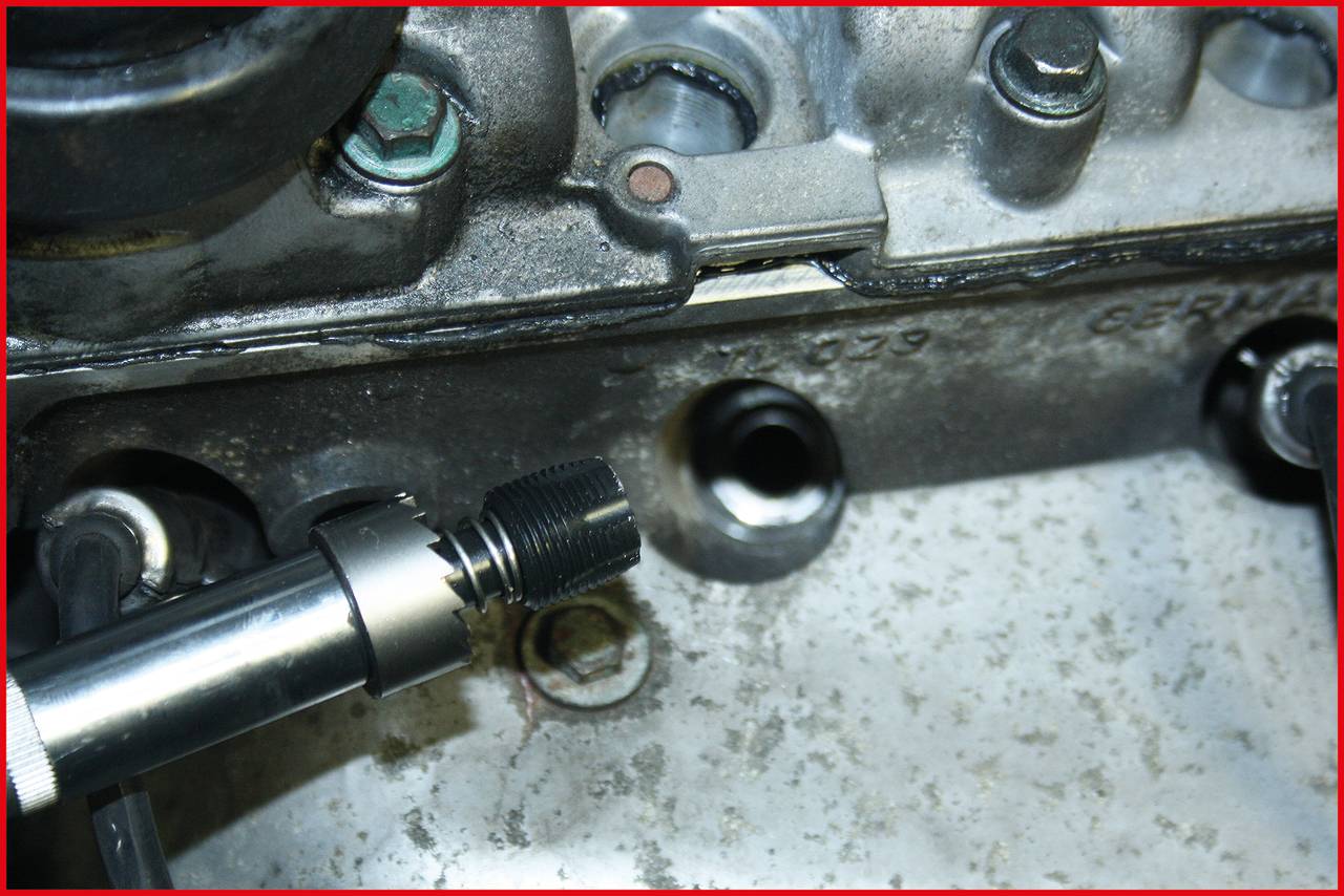 Nahaufnahme eines Motorbauteils mit einem abgedichteten Sensor, der in einen Metallblock eingeschraubt ist. Oberflächen sind leicht verölt.