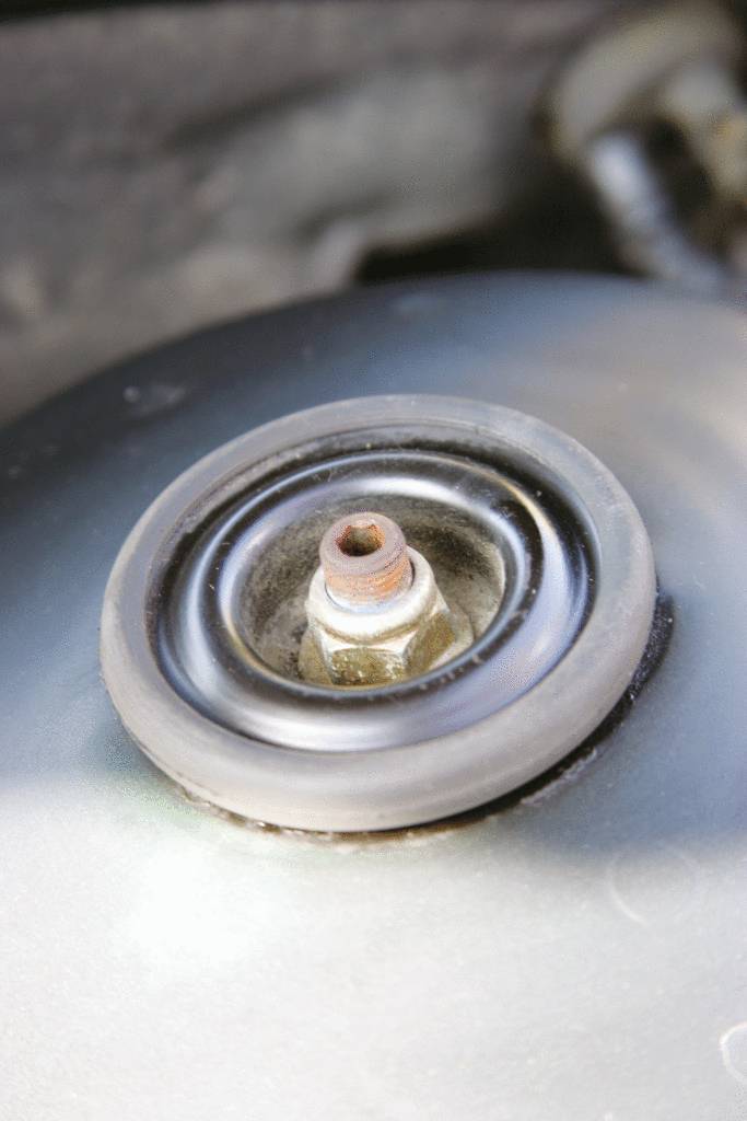 Eine Nahaufnahme einer Metallmutter mit einer Gummischeibe auf einer metallischen Oberfläche, Teil eines technischen Geräts.