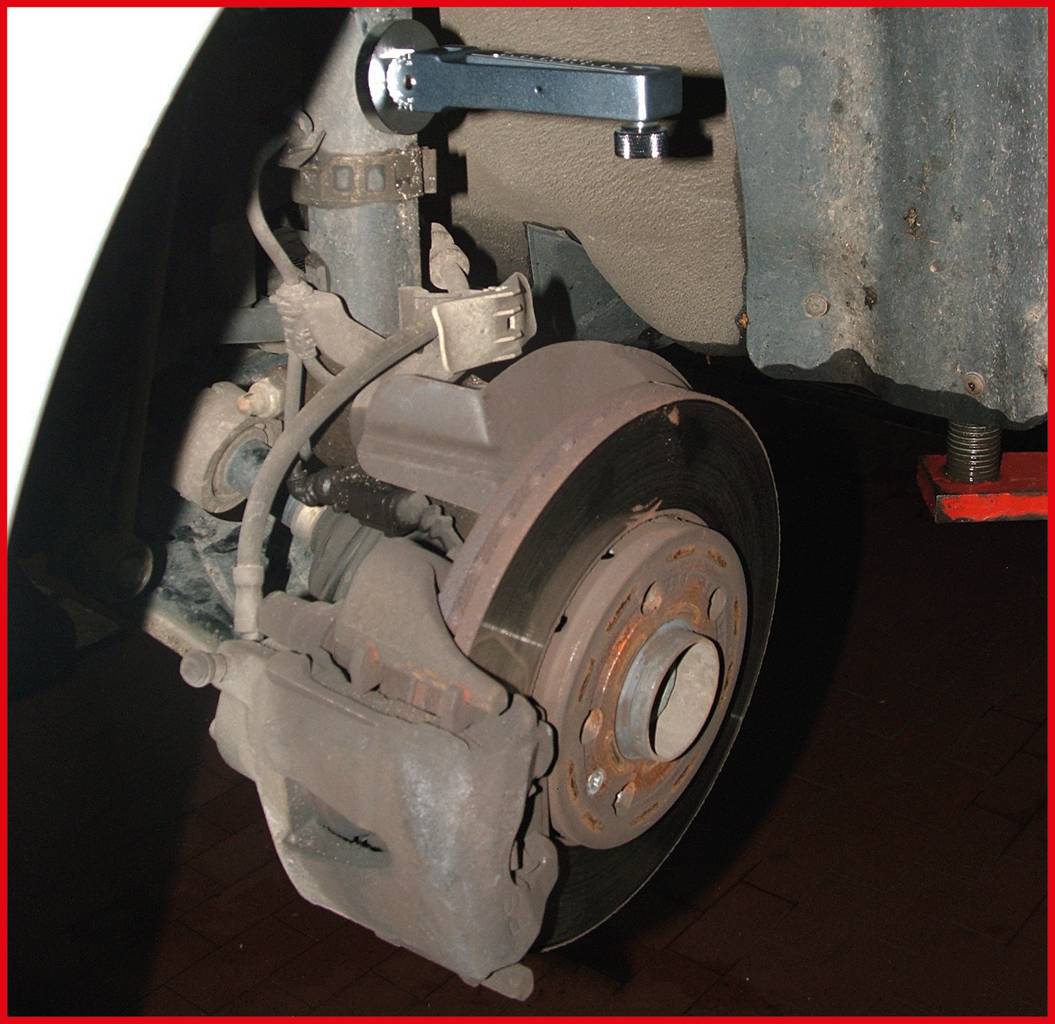 Fahrzeugbremsanlage während der Wartung. Vorderer Bremssattel und Bremsscheibe sind sichtbar. Schraubenschlüssel oben zum Lösen der Schrauben.