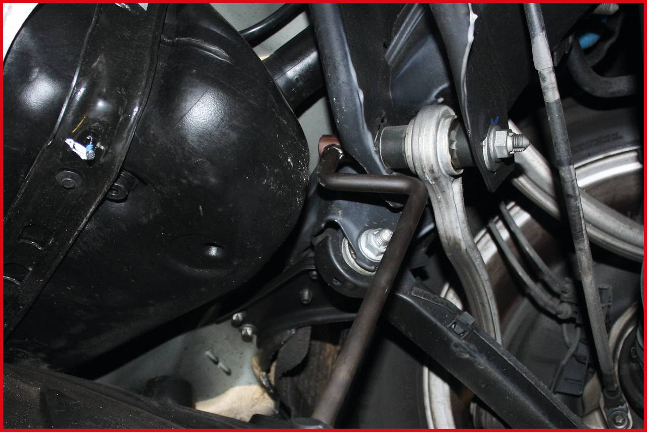 Nahaufnahme eines Autoteils, das eine Federungskomponente mit Verbindungselementen zeigt. Hauptsächlich mechanische Details sichtbar.