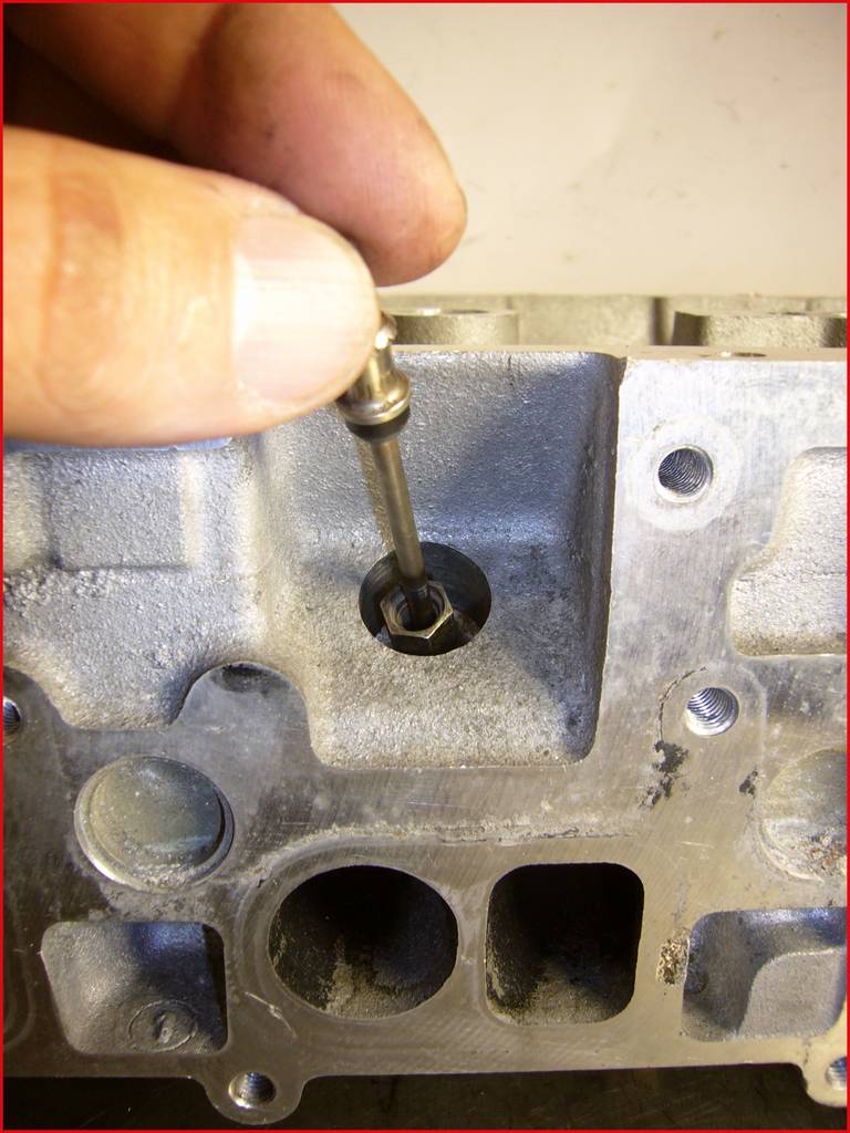 Nahaufnahme einer Hand, die einen kleinen Metallstift in ein Loch einer strukturierten Metalloberfläche einsetzt.