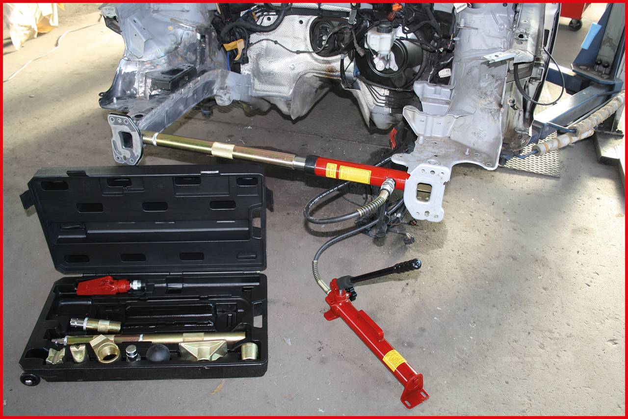 Ein Mechanikerwerkzeugkasten mit hydraulischen Spreizwerkzeugen auf einer Werkstattbodenszene, die zur Fahrzeugreparatur genutzt werden können.