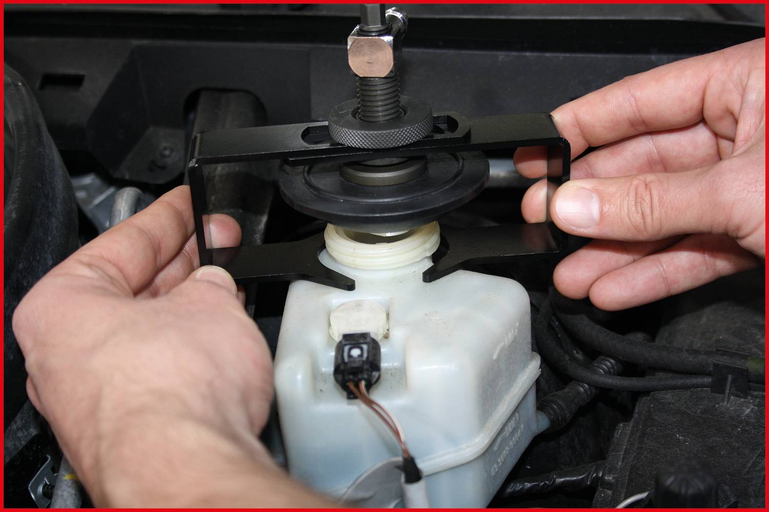 Eine Person montiert ein Werkzeug zum Entlüften des Bremssystems auf einem Bremsflüssigkeitsbehälter in einem Fahrzeug.