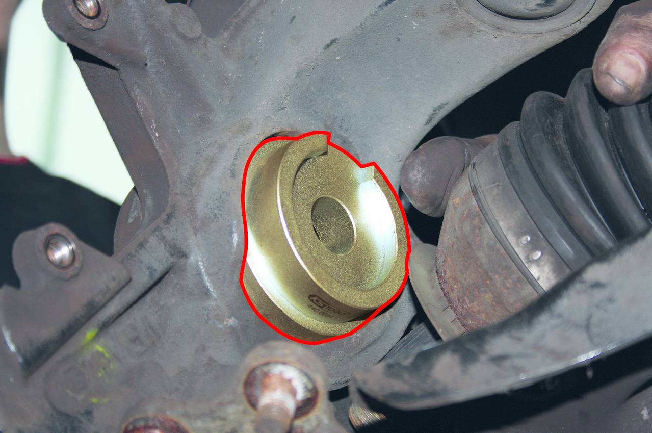Metallbuchse in einer Automechanik, betont durch rote Umrandung. Nahe an einem Antriebswellenlager, Teile sind verrostet.