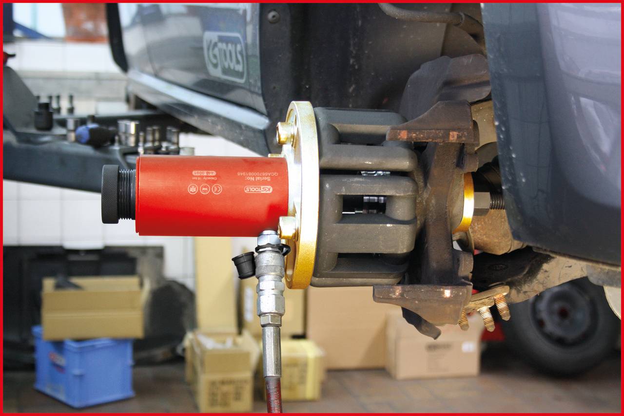 Auto in Werkstatt, ausgerichtet auf Wagenheber, zeigt Bremssattel und Aufhängung für Reparatur oder Wartung.