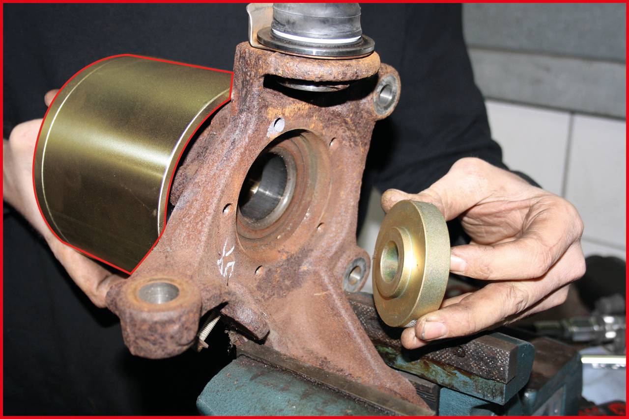 Eine Person hält ein rostiges Autoteil und ein kleineres Metallteil. Dies zeigt den Austausch oder die Reparatur eines Fahrzeuglagers.