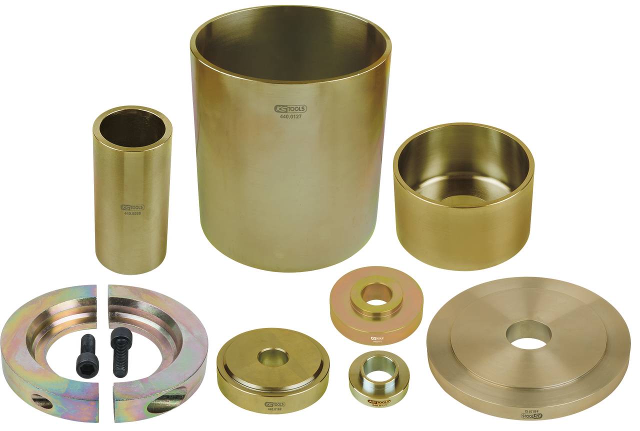 Verschiedene goldene, zylindrische Metallformen und -ringe in unterschiedlichen Größen sind auf einer flachen Oberfläche angeordnet.