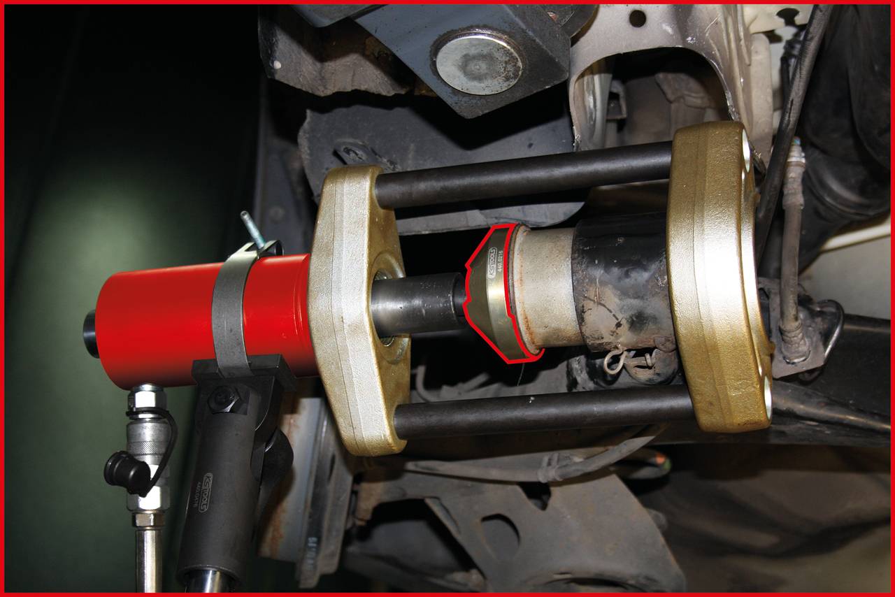 Ein Drehmomentwerkzeug spannt eine Metallhülse in einem Fahrzeugchassis. Es wird für die Wartung oder den Austausch von Komponenten verwendet.