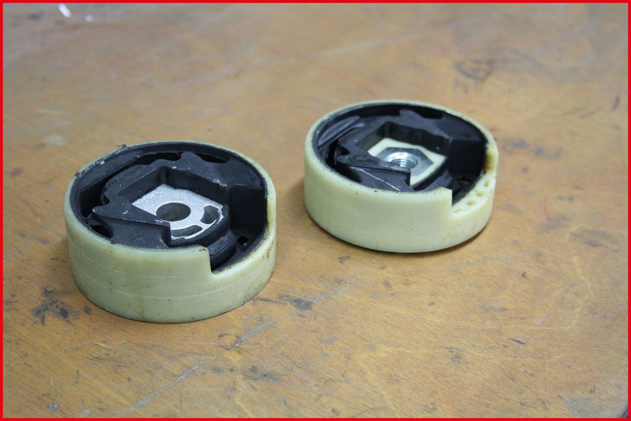 Zwei runde mechanische Bauteile auf einer Holzoberfläche. Die Komponenten zeigen eine innere Metallstruktur und sind von Kunststoff umgeben.