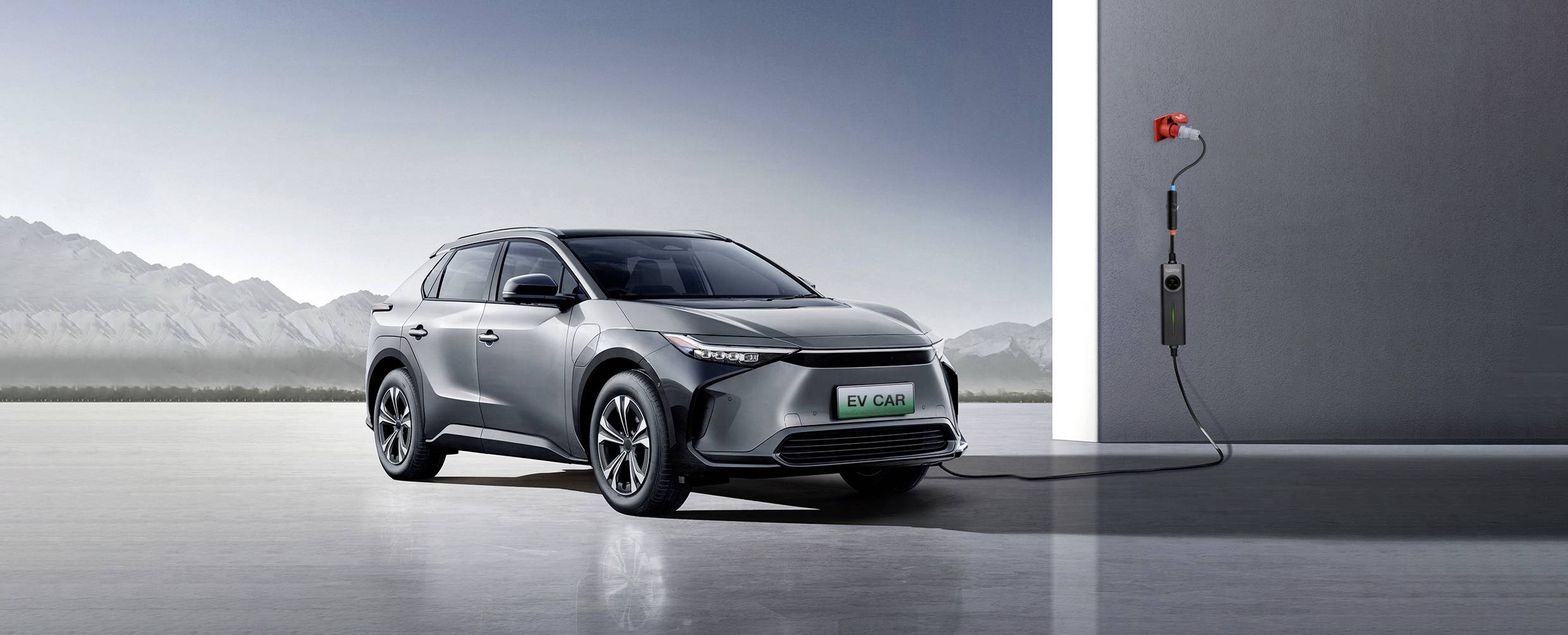 Ein graues Elektroauto wird in einer futuristischen Umgebung geladen, wobei ein Ladekabel von einer Wandstation zum Auto führt.