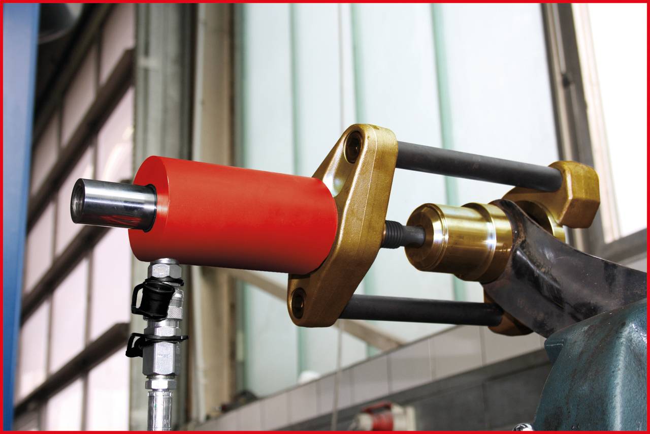 Metallische Maschine mit roten und goldenen Komponenten, wahrscheinlich ein Press- oder Bearbeitungswerkzeug, in industrieller Umgebung.