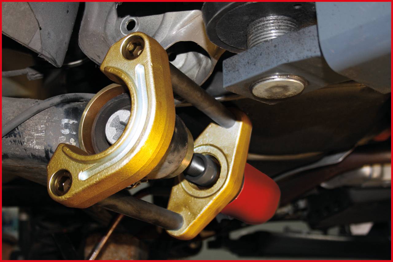 'Automobilteilmontage: Oberseite eines Stoßdämpfers mit goldener Halterung und Schraubverbindung, sichtbar in einer Werkstattumgebung.'