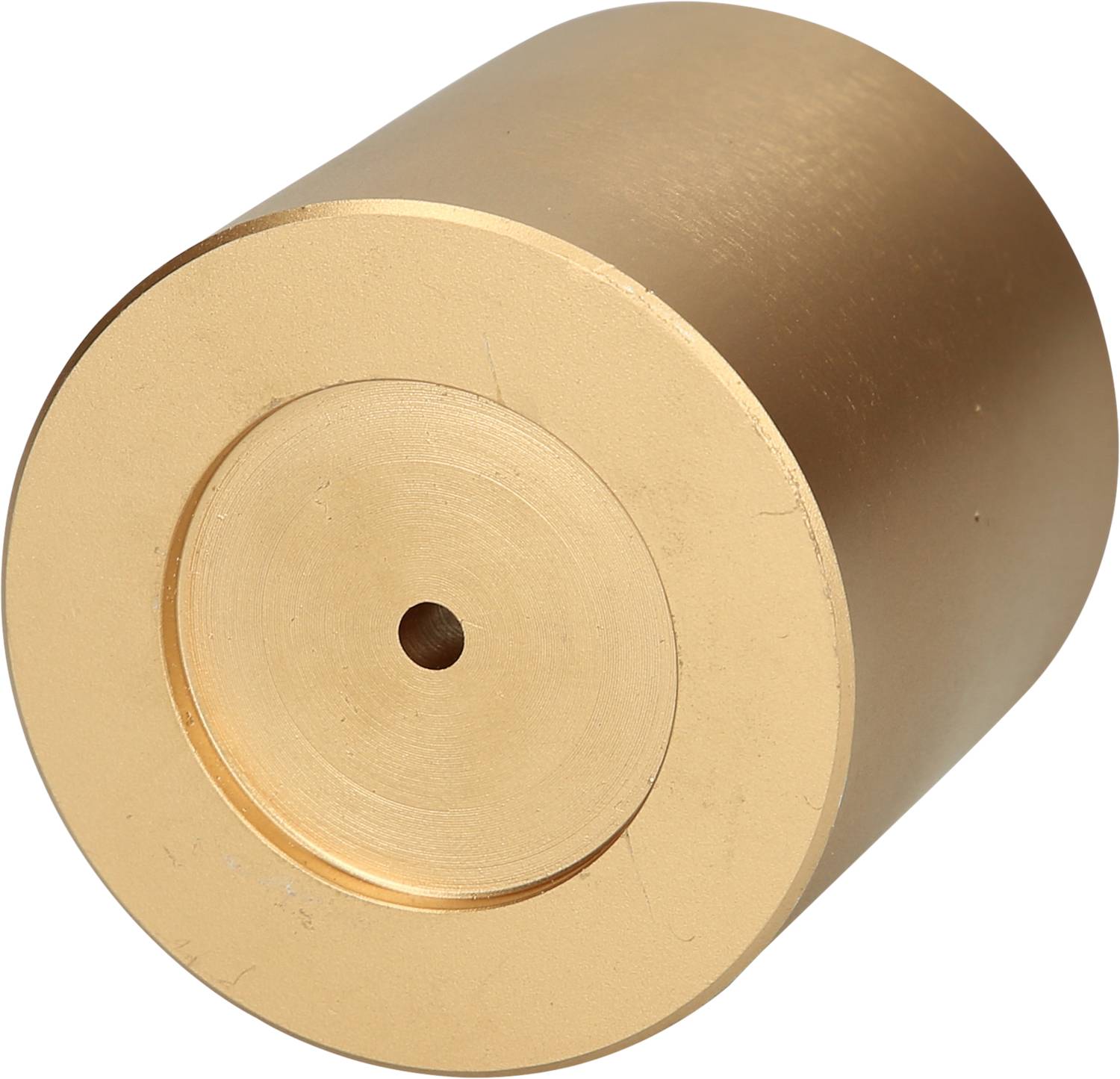 Ein zylindrischer, goldfarbener Metallblock mit einer kleinen zentralen Bohrung.