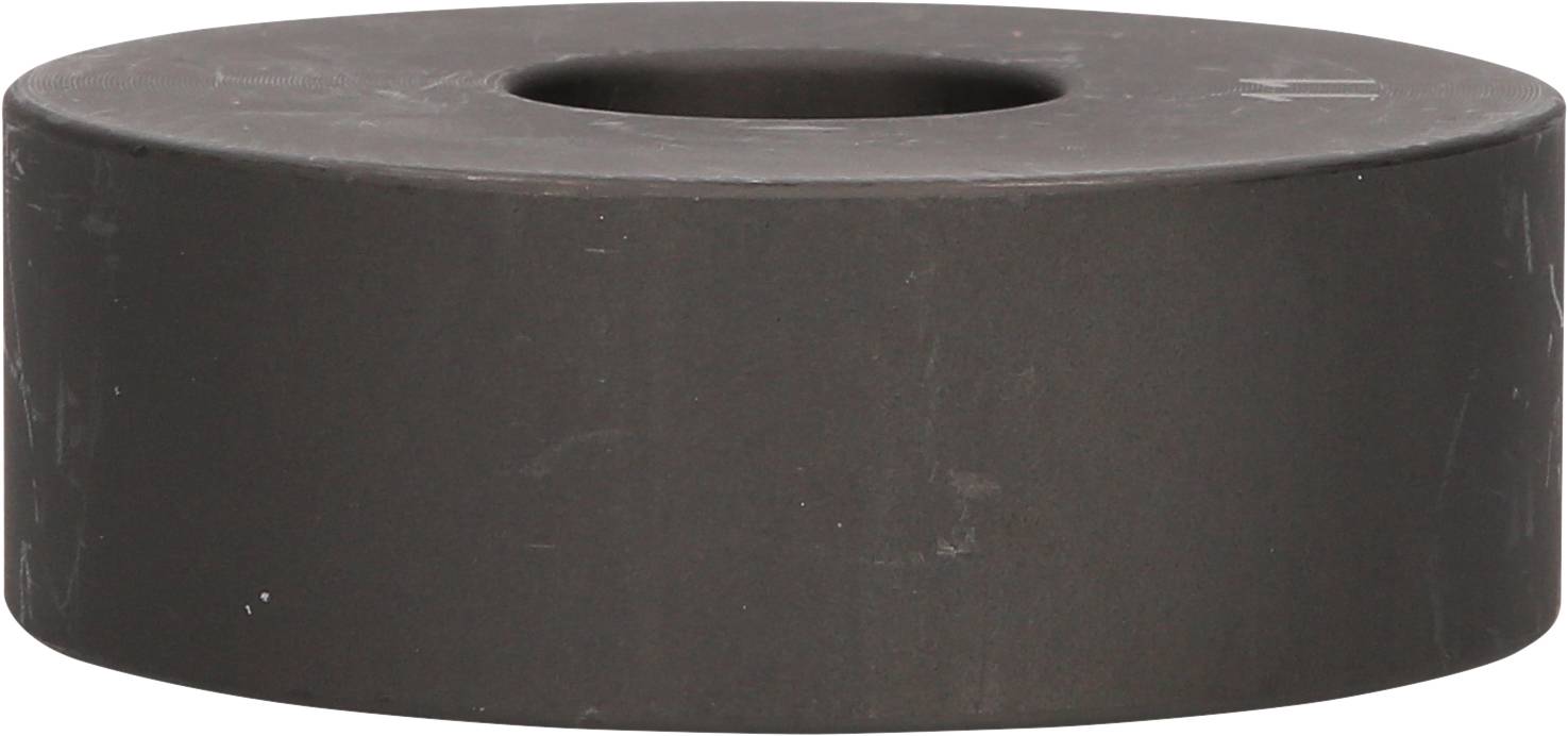 Ein runder, schwarzer Magnet mit einem Loch in der Mitte, das auf einer hellen Oberfläche liegt.