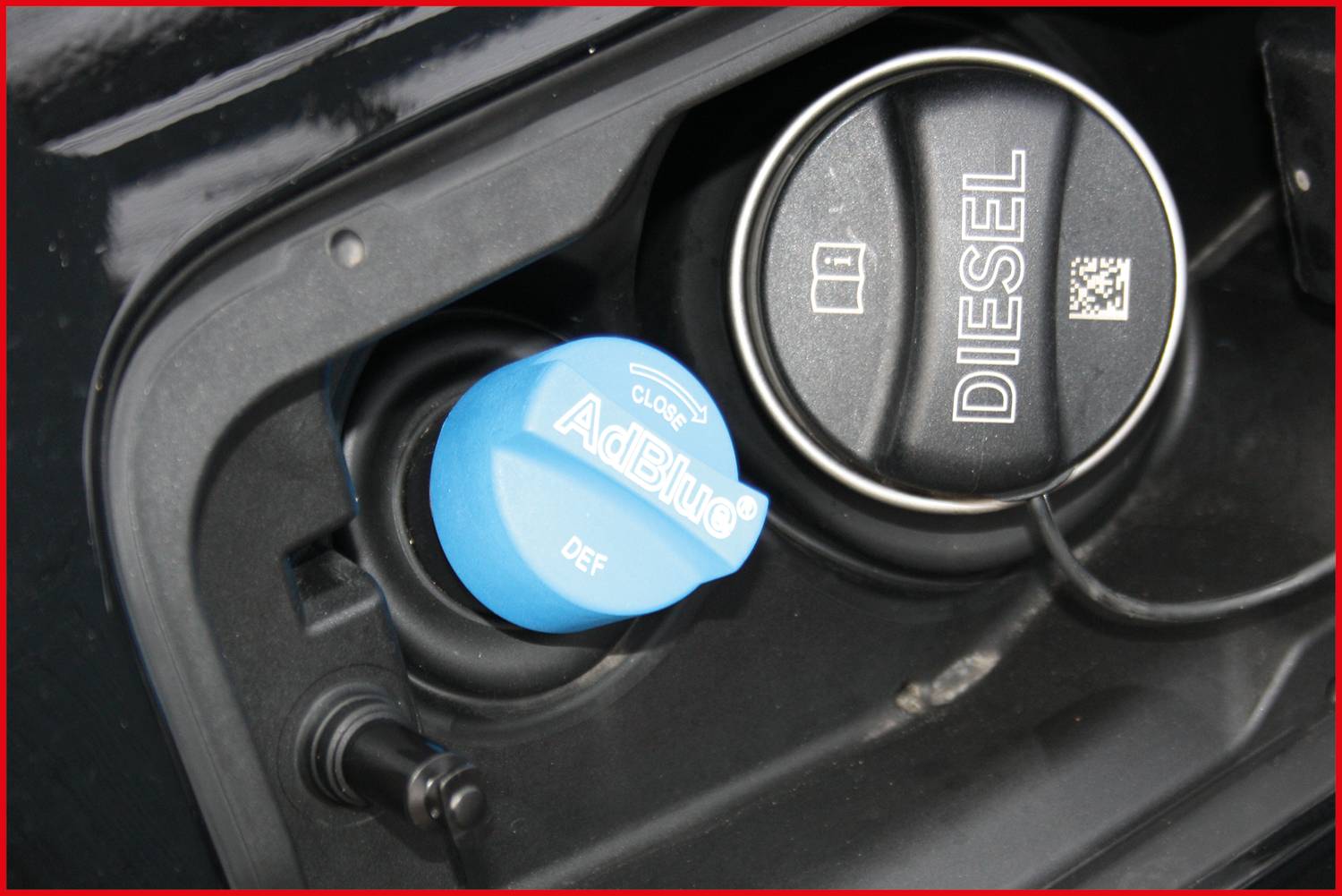 Ein geöffneter Tankdeckel eines Fahrzeugs. Links ist ein blauer 'AdBlue' Verschluss, rechts ein schwarzer Diesel-Verschluss. Beide sind beschriftet.