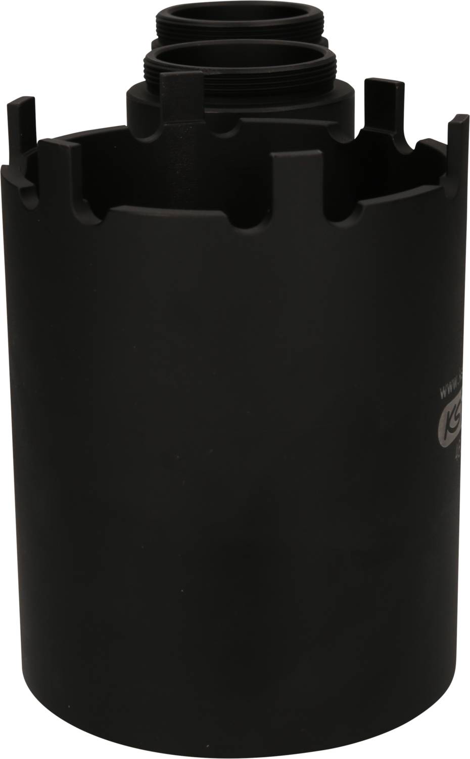 Eine schwarze, zylindrische Metallhülle mit gezacktem Rand und Gewindeöffnungen oben. Funktion unklar.
