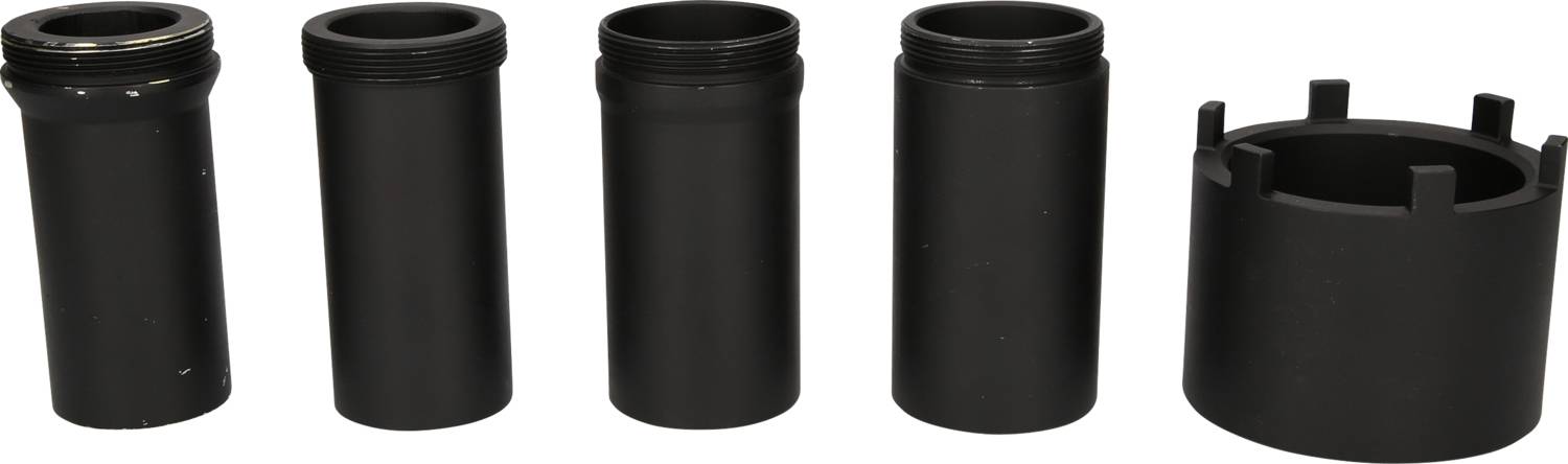 Fünf schwarze Zylinder in unterschiedlicher Form und Größe stehen nebeneinander auf einer weißen Fläche.