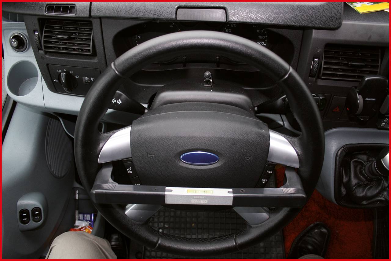 Lenkrad eines Autos aus Fahrersicht mit Instrumententafel und Armaturen, zeigt Steuerungs- und Bedienelemente im Fahrzeug.