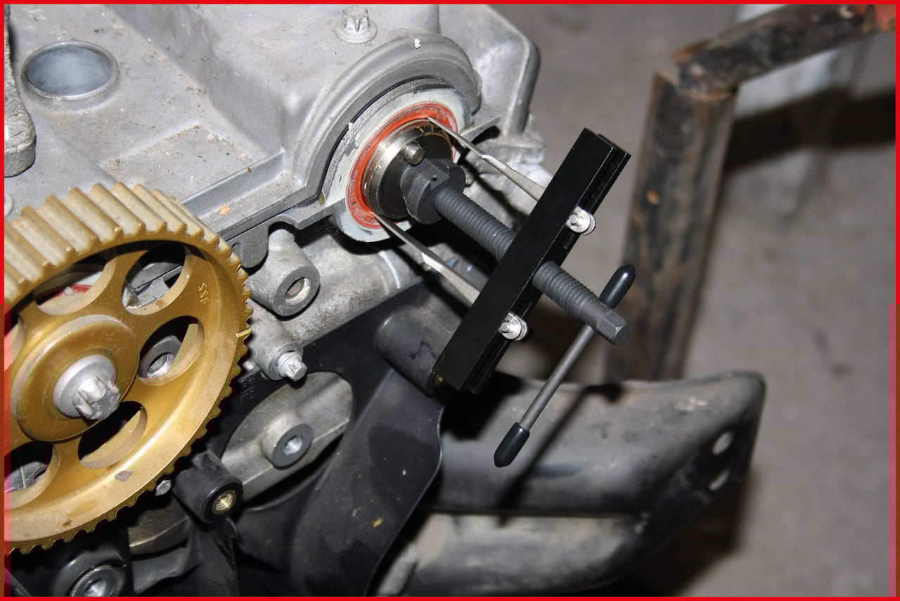 Ein Motor mit einem Zahnrad und einem schwarz-silbernen Werkzeug zur Konstruktion oder Reparatur. Im Hintergrund unscharfe Autoteile.