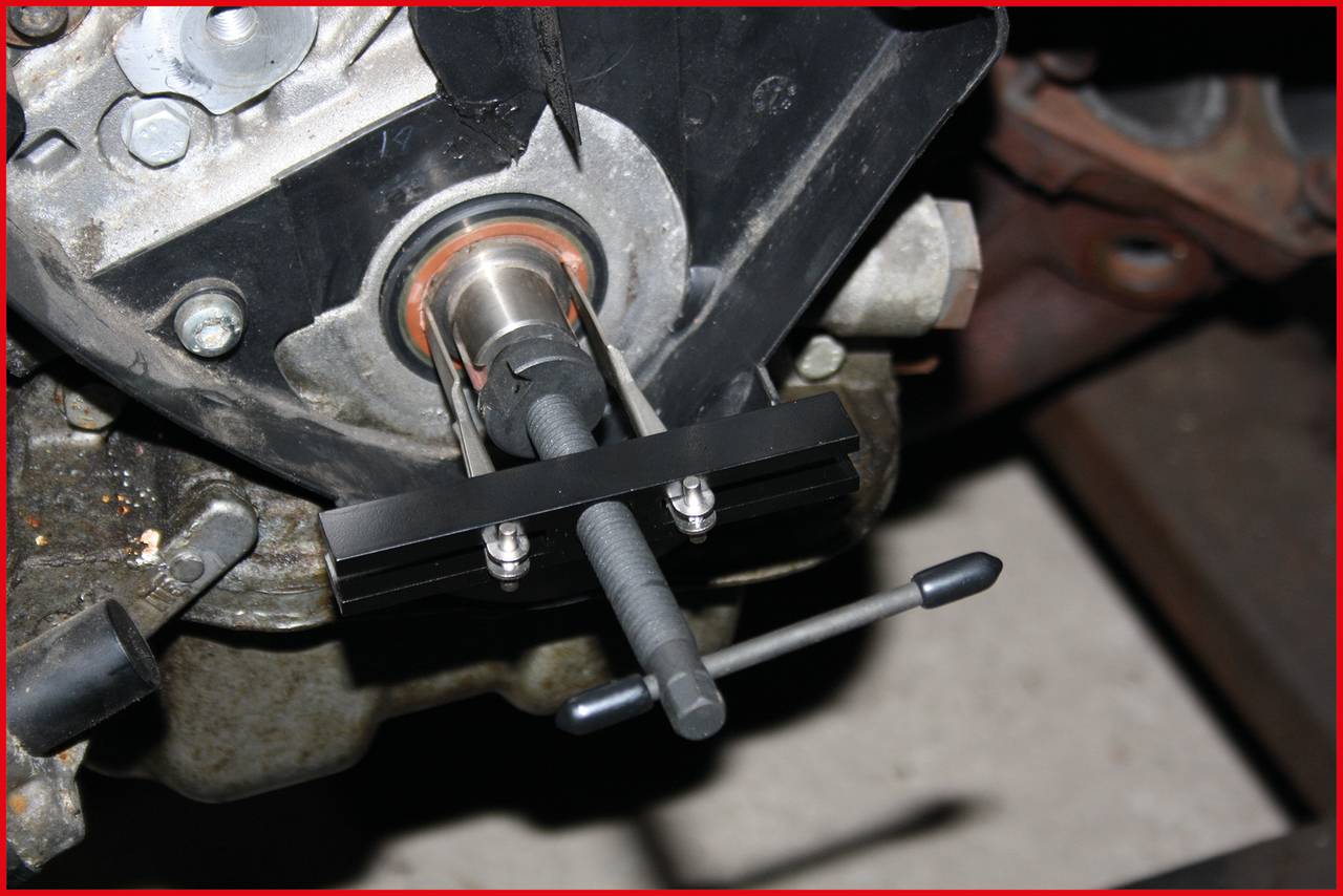 Ein Abzieherwerkzeug wird an einem Motor eingesetzt, um ein Lager oder eine Buchse zu entfernen. Der Motorblock ist teilweise sichtbar.