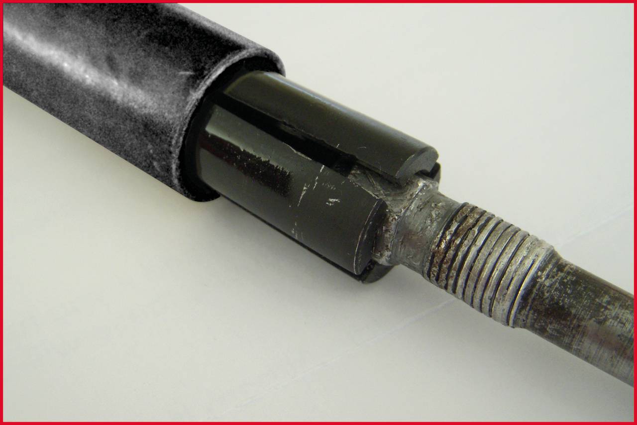 Nahaufnahme eines Metallbackens einer Bohrvorrichtung mit abgenutztem Gewinde, das in einen schwarz lackierten Zylinder übergeht.