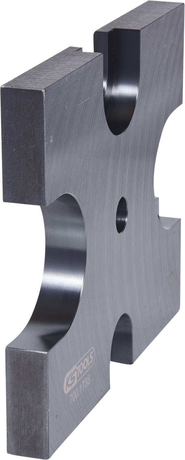 Eine Metallform mit Aussparungen, die an die Form eines Kreuzes erinnert, auf einer neutralen Oberfläche.