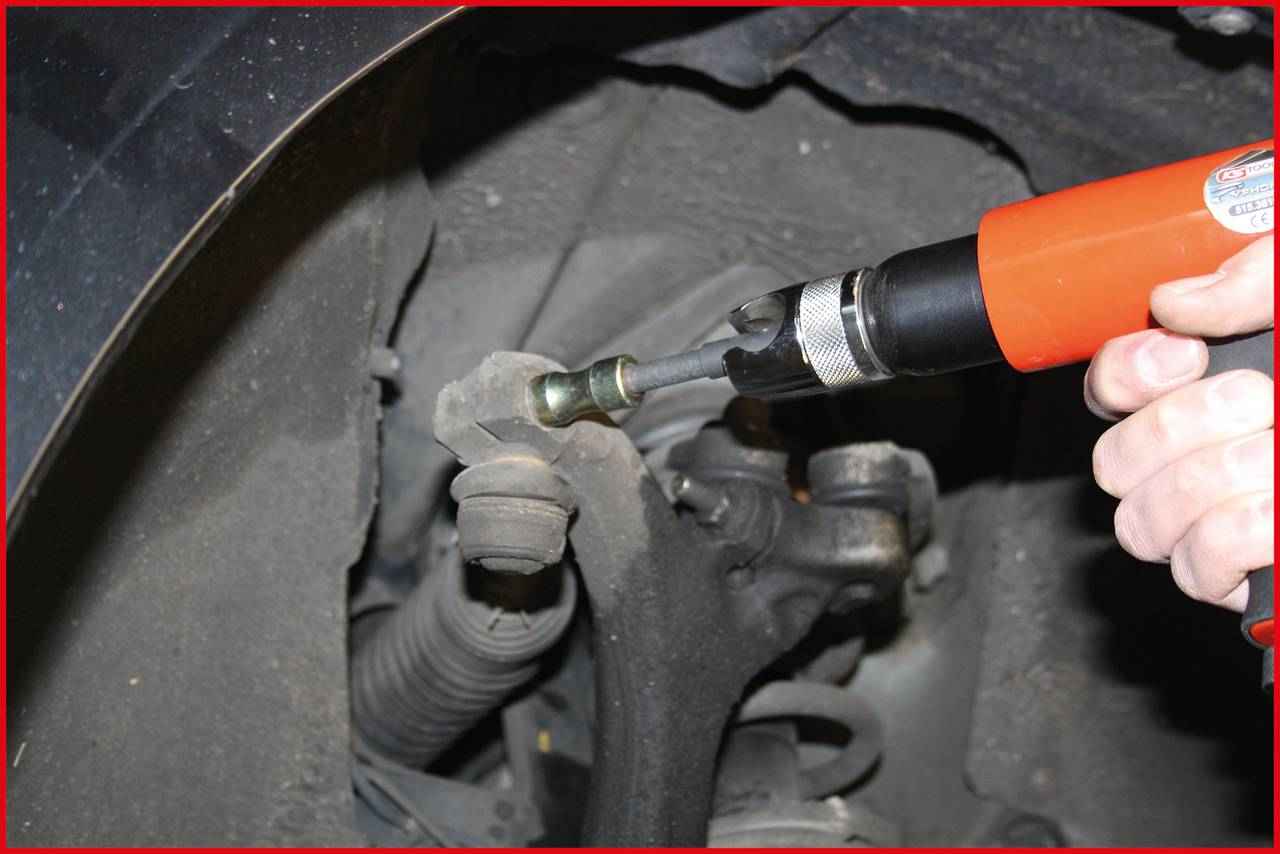 'Nahaufnahme eines Werkzeugs zum Entfernen einer Radschraube eines Fahrzeugs. Ein rotes Elektrogerät wird von einer Hand gehalten.'