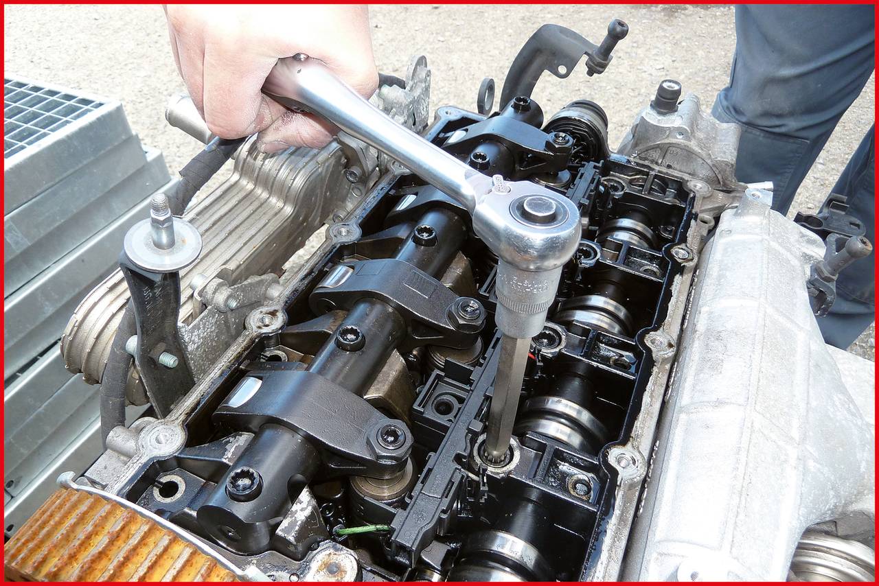 Eine Person verwendet einen Drehmomentschlüssel zur Reparatur eines Motors, konzentriert auf die Zylinderköpfe und Ventile.