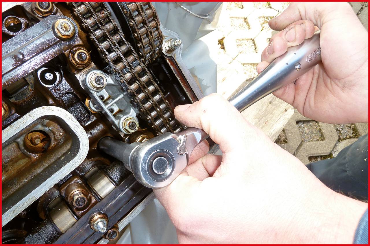 'Hände reparieren einen Motor mit einem Schraubenschlüssel. Kettenmechanismus und Zahnräder sind sichtbar. Technische Arbeiten.'