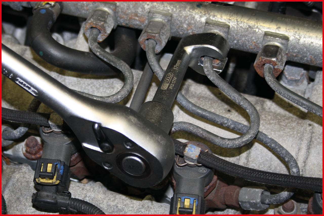 Nahaufnahme eines Autowerkzeugs, das an der Verkabelung und den Anschlüssen eines Motors arbeitet. Schraubenschlüssel ist am Einsatz.