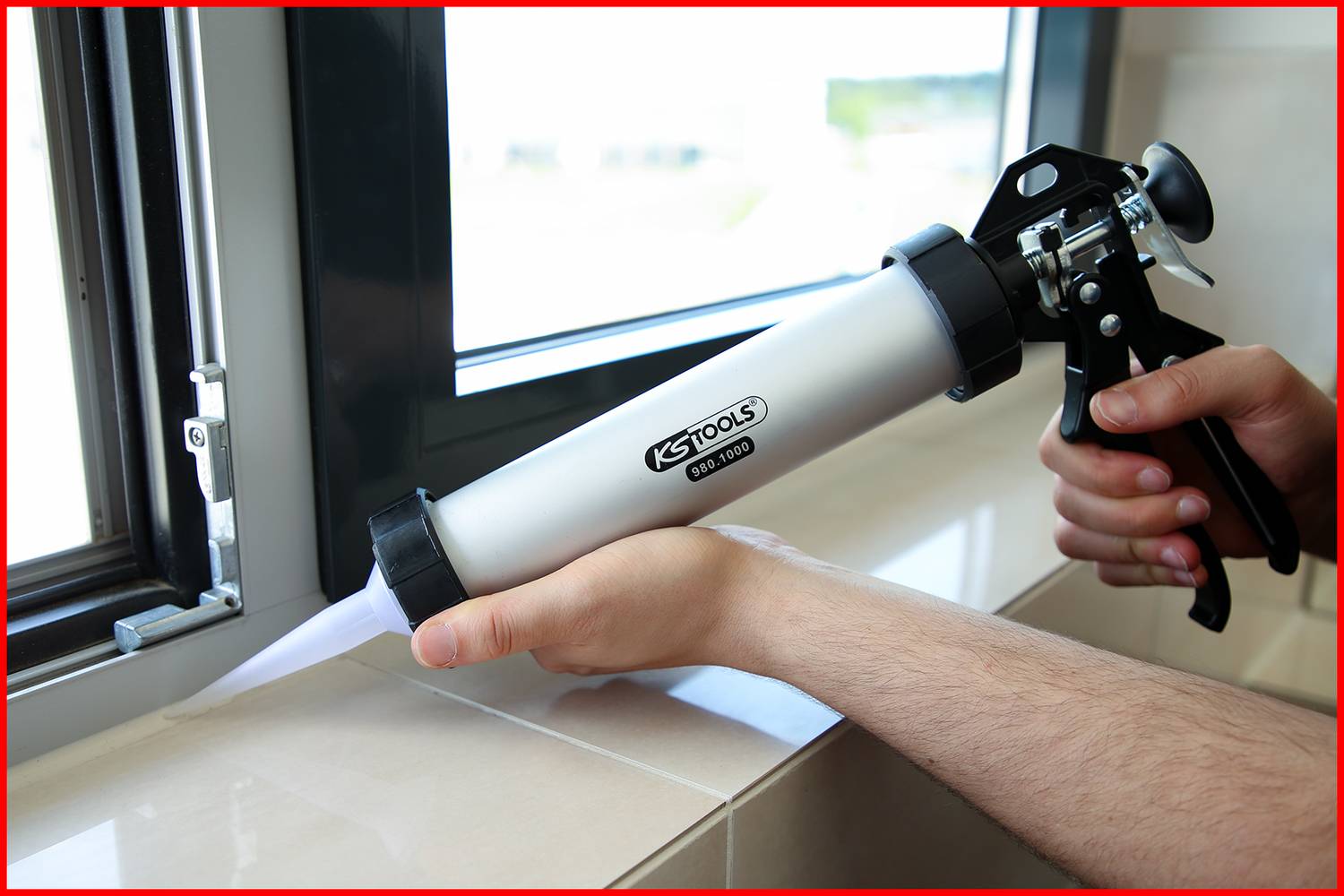 'Eine Person dichtet mit einer Kartuschenpistole die Kante eines Fensterrahmens ab.'