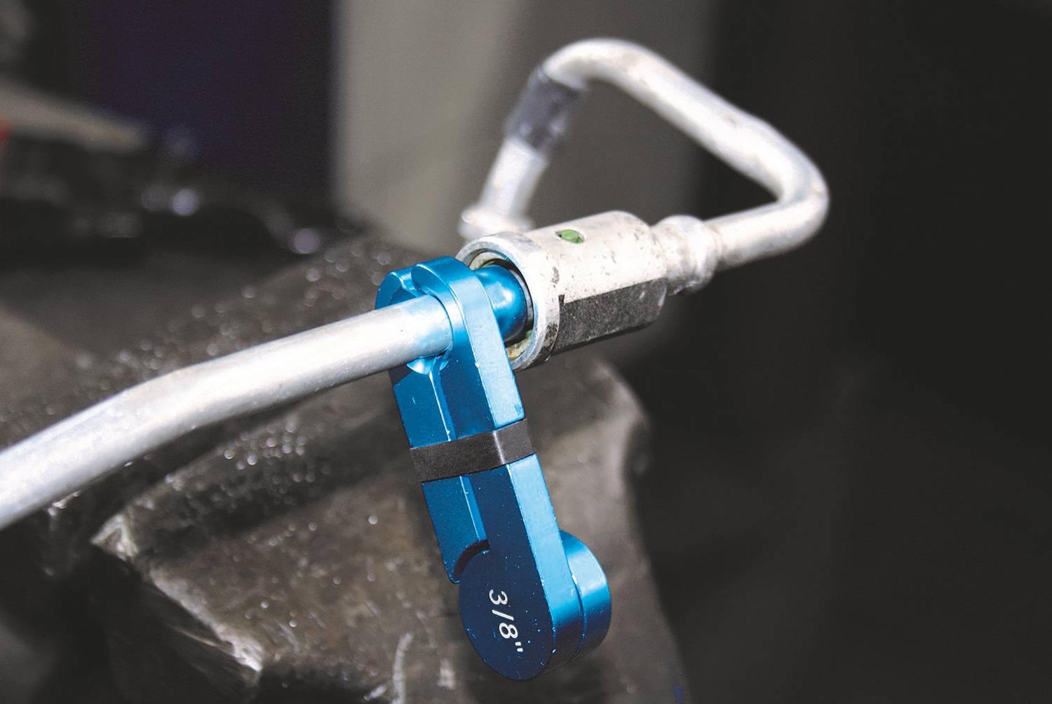 Ein blauer Drehmomentschlüssel befestigt an einer Metallleitung in einer Werkstattumgebung, zeigt die Größe 3/8.