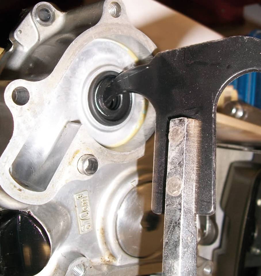 Nahaufnahme eines Mechanikers, der ein schweres Werkzeug verwendet, um ein Lager in einem Maschinenbauteil zu montieren oder auszutauschen.