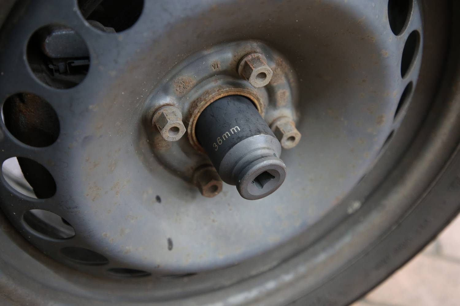 Ein Radnaben mit rostigen Schrauben und einem 36-mm-Schlüsselaufsatz in einer Autowerkstatt.
