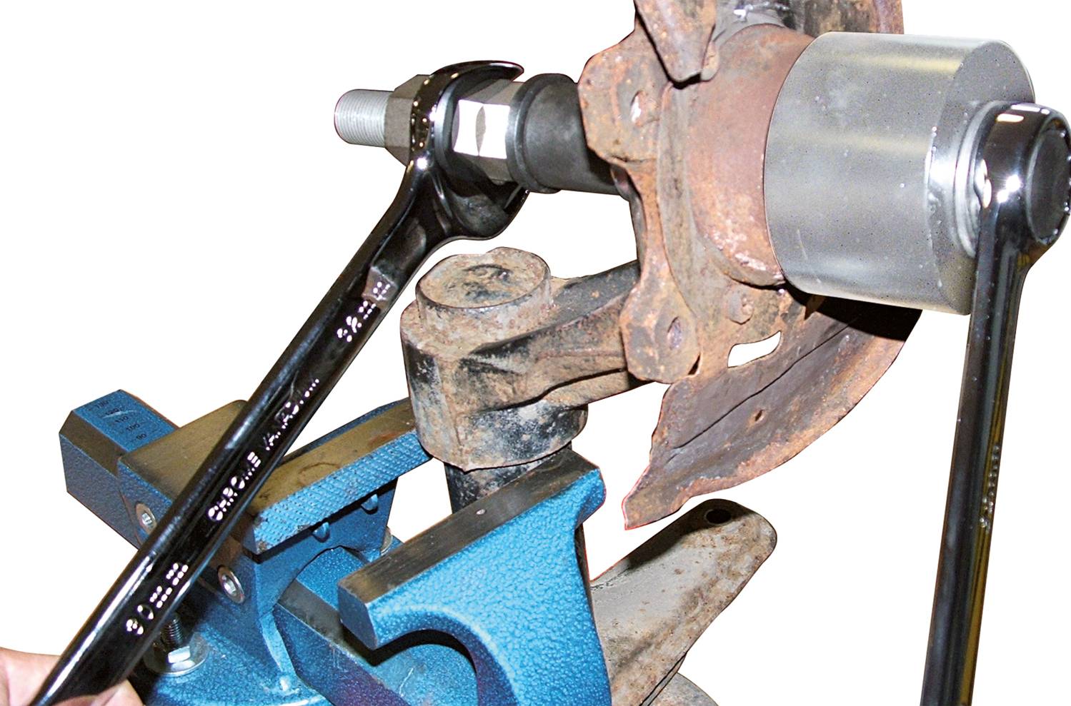 'Nahaufnahme eines Schraubenschlüssels, der an einem rostigen Autoteil befestigt ist, das in einem Schraubstock eingespannt wurde.'