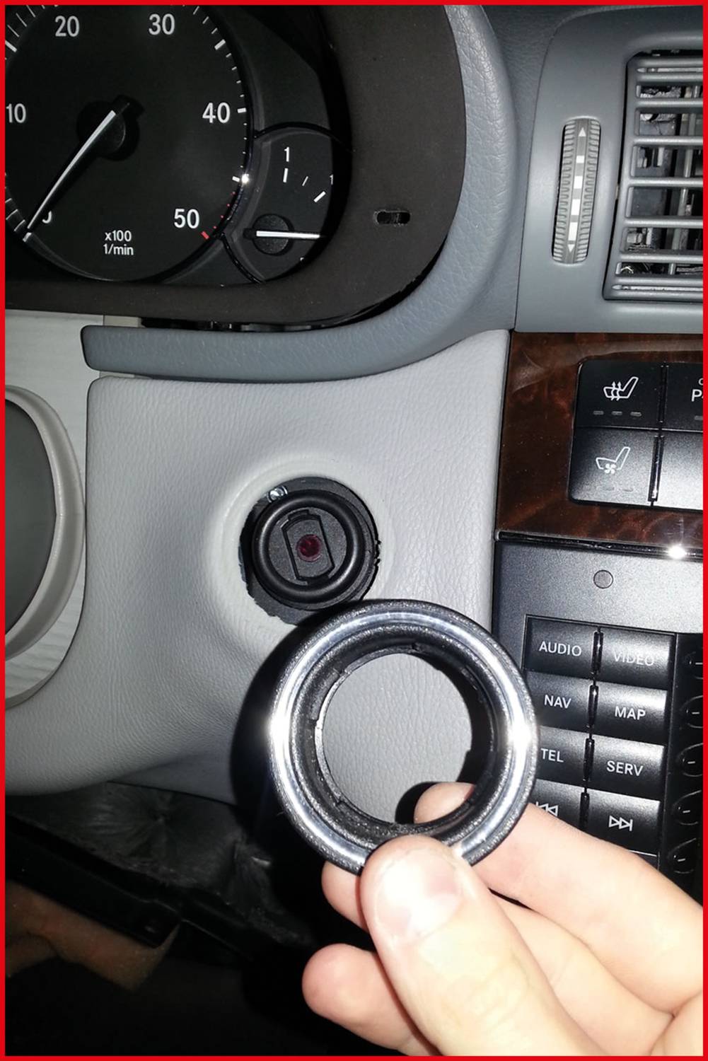 Person hält einen Ring in der Hand, der zu einem Autoschloss gehört. Das Armaturenbrett und die Instrumententafel des Autos sind sichtbar.
