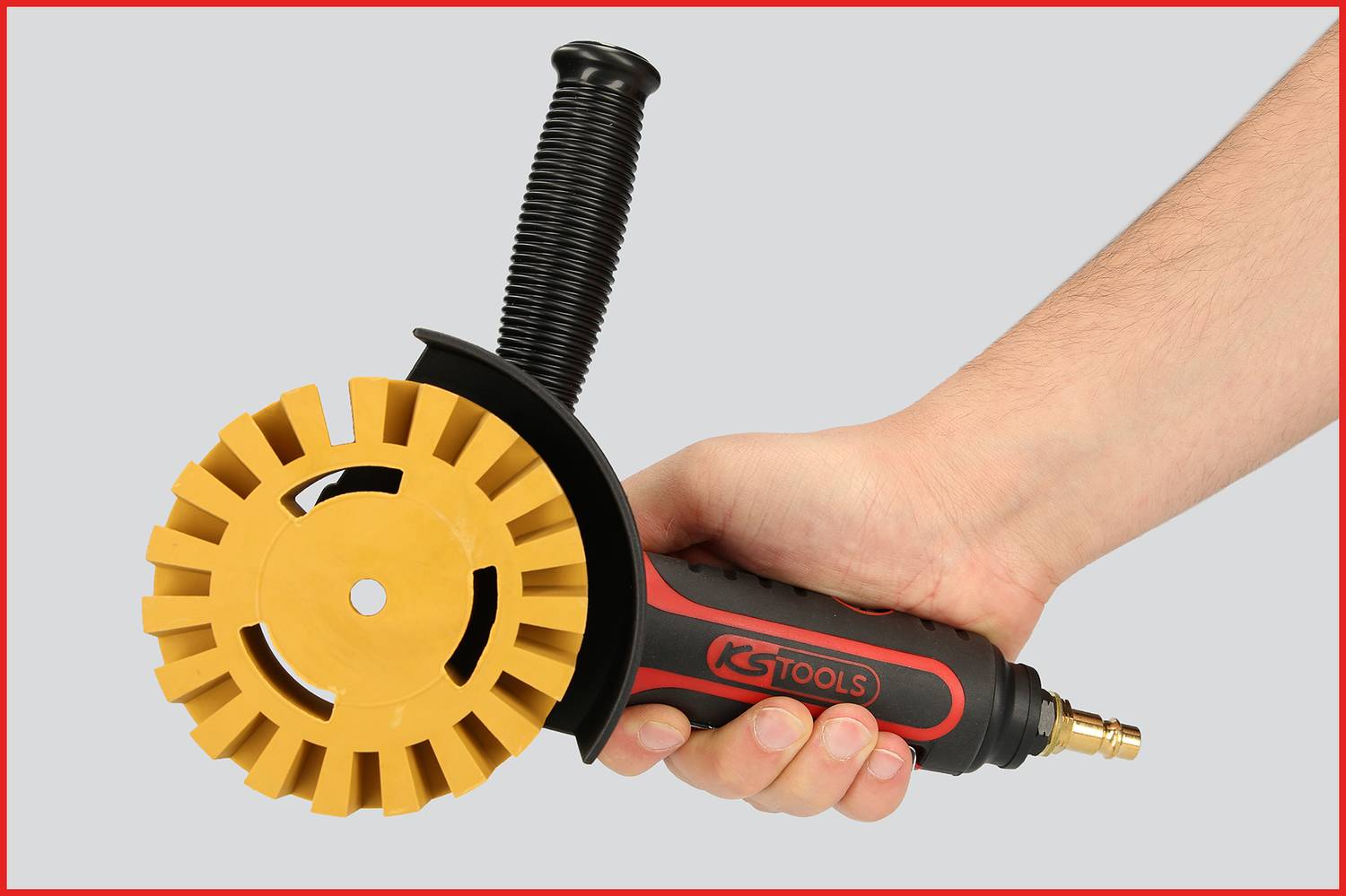 Eine Person hält ein elektrisches Werkzeug mit schwarzem Griff und gelbem, zahnradförmigem Kopf. Das Gerät ist von KS Tools.
