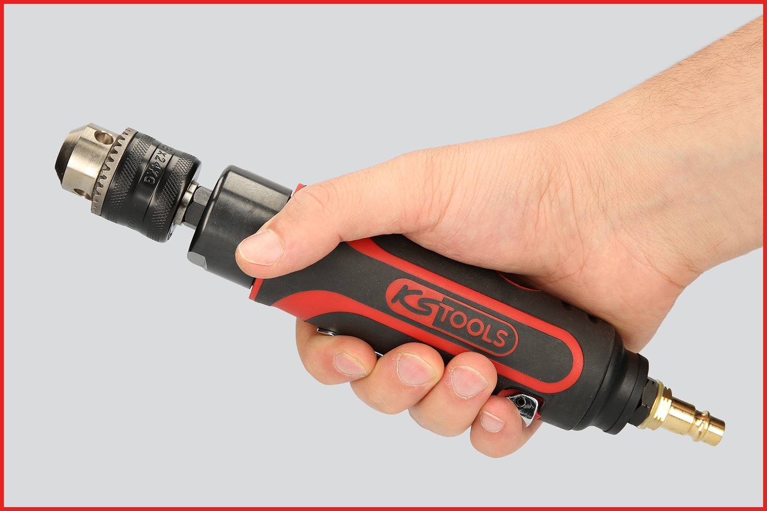 Eine Hand hält einen rot-schwarzen pneumatischen Schrauber mit 'KS Tools'-Logo. Das Werkzeug hat eine Metallspitze für Schraubarbeiten.