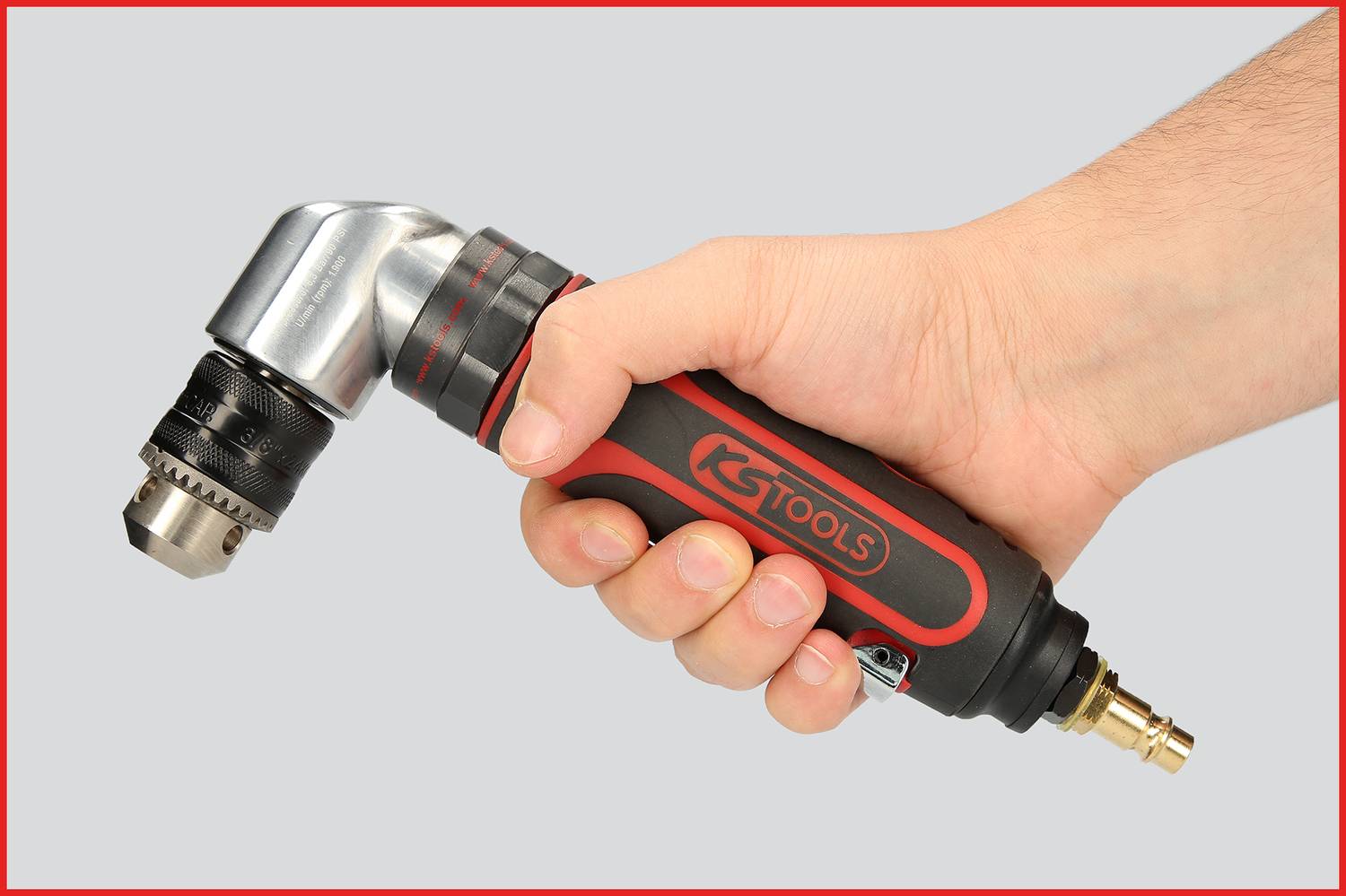 Eine Hand hält einen Pneumatik-Winkelbohrer von KS Tools, geeignet für schwer zugängliche Stellen. Der Hintergrund ist einfarbig grau.
