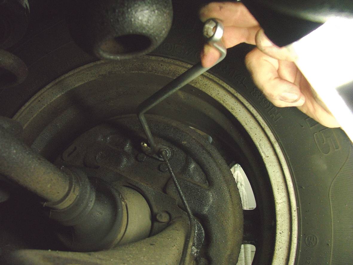 Eine Hand zieht ein Ventil zur Notentriegelung der elektrischen Parkbremse.