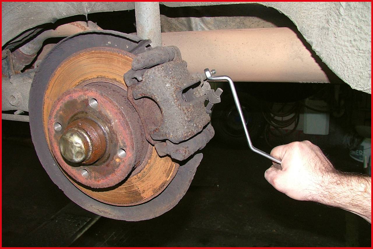Ein Auto-Bremssystem, bei dem ein Rostlöser an der Radnabe und der Bremsscheibe verwendet wird. Eine Hand hält das Werkzeug.
